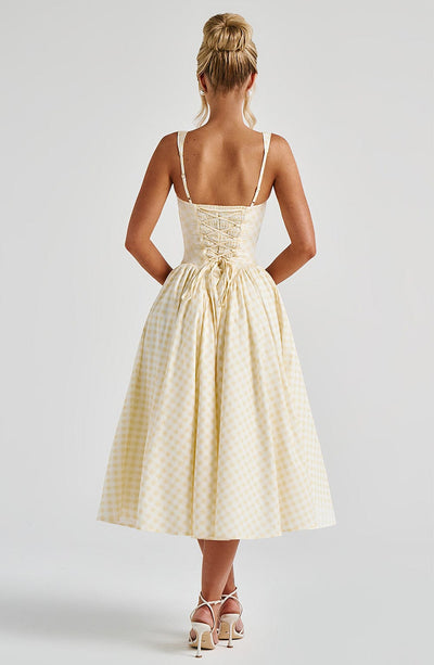 Back view of a light yellow gingham midi dress, featuring a detailed lace-up back closure.
