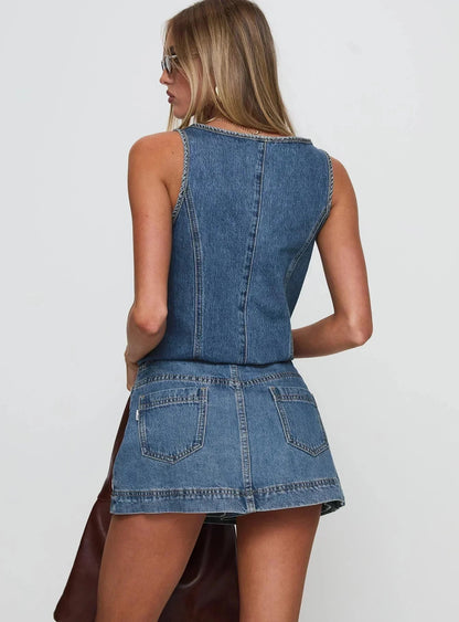 Back view of a woman showing the blue denim sleeveless crop top and mini skirt with back pockets for women