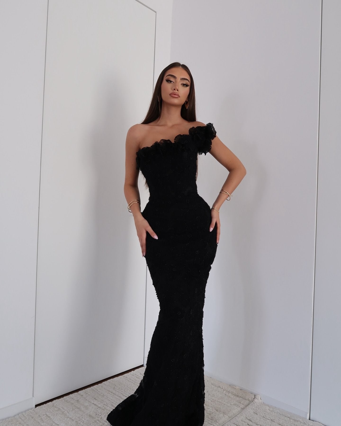 Full-length view of a woman wearing a black floral one-shoulder maxi dress for formal events.