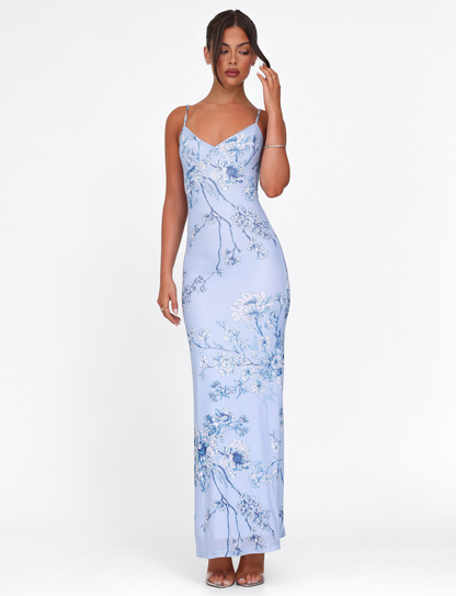 Full-length view of a light blue floral maxi dress with thin straps and a form-fitting silhouette, showcasing the intricate blue and white flower print.