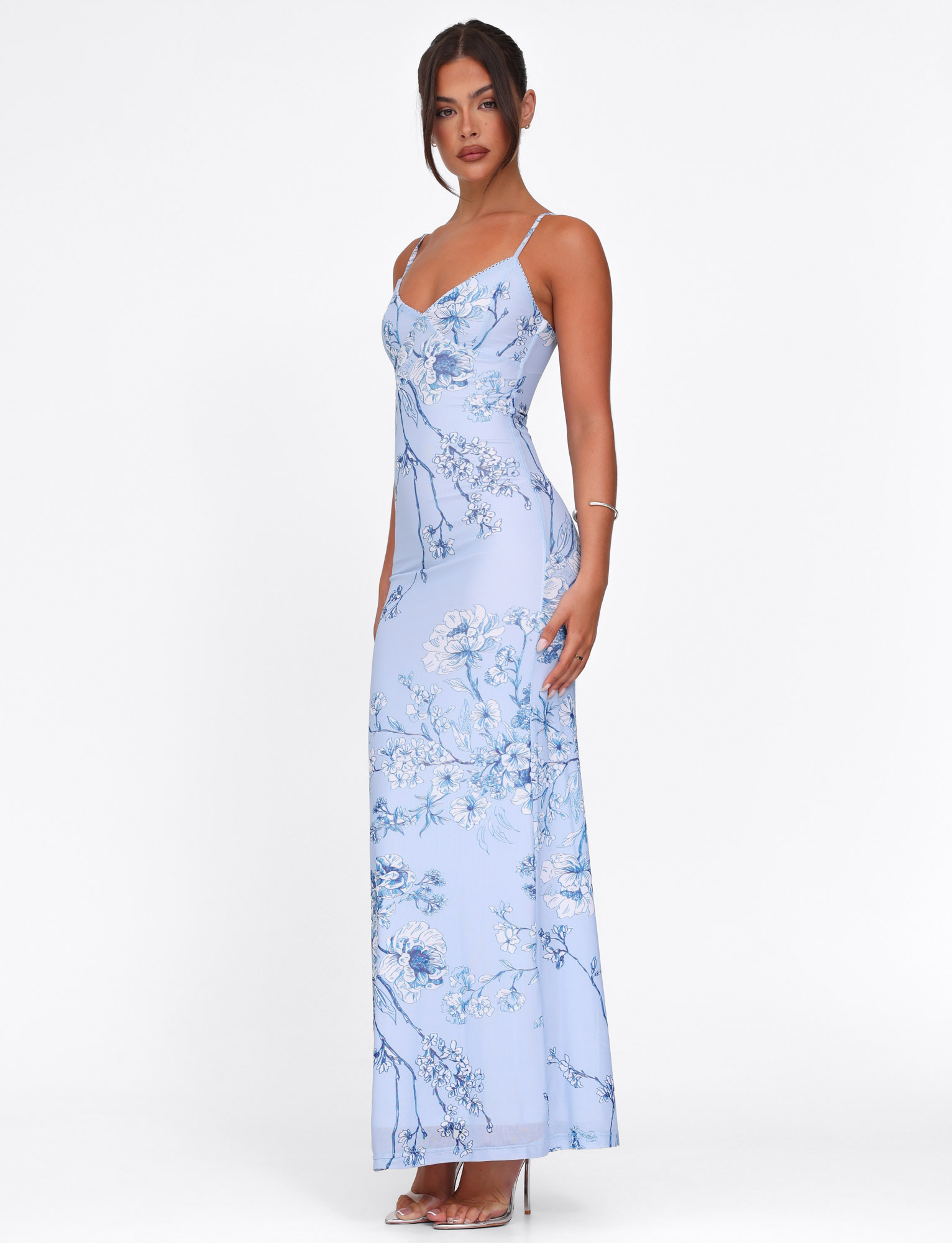 Side profile of a light blue floral maxi dress, emphasizing the elegant drape and the full length of the dress with its floral print.