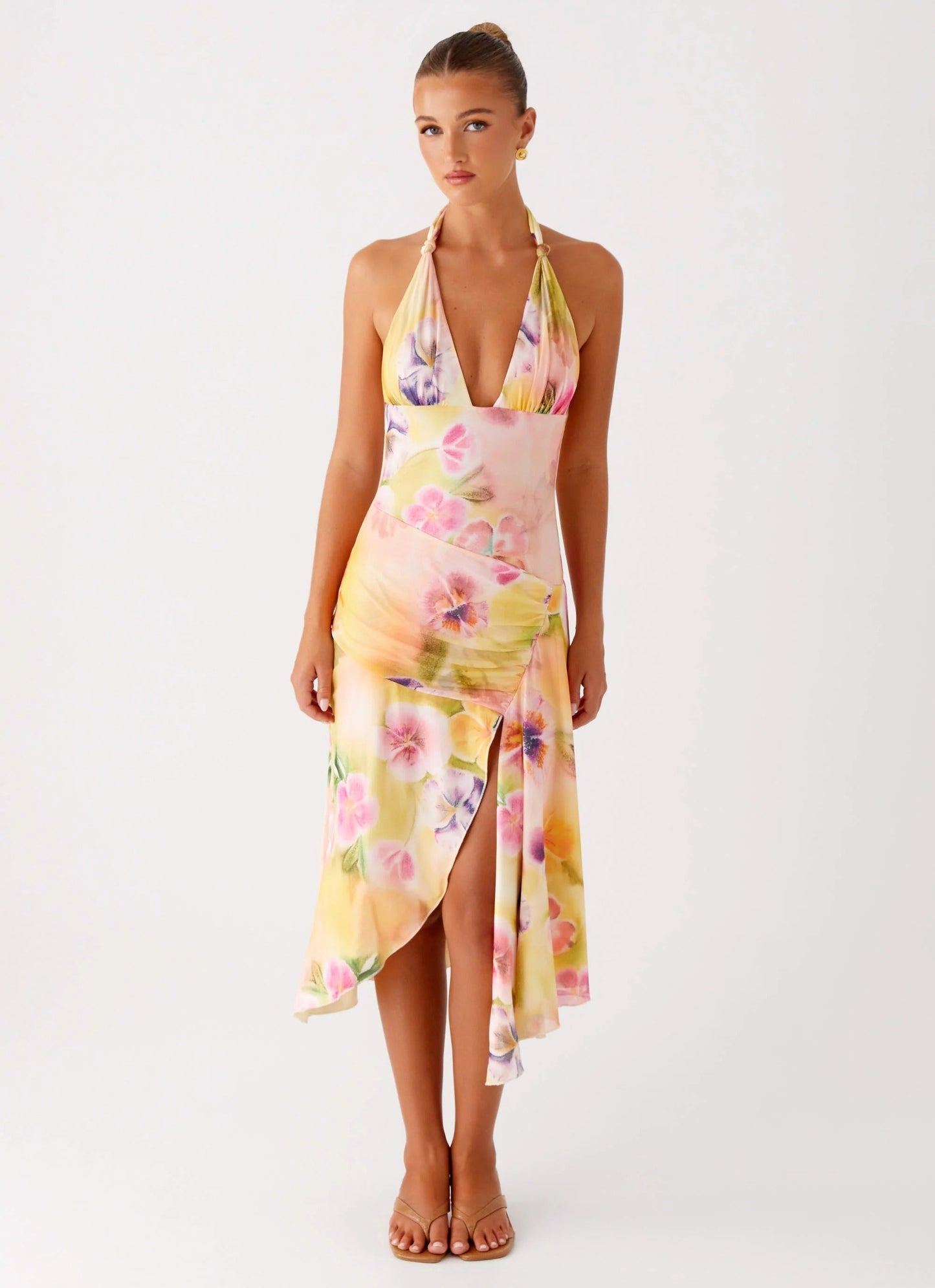 Front view of a woman posing in the vibrant floral halter midi dress with a high side slit for women.