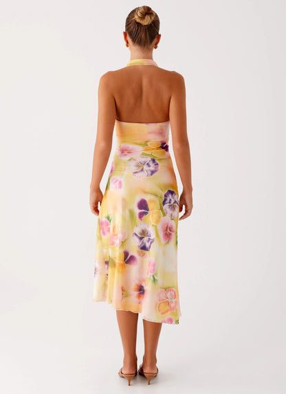Back view of a woman showcasing the bare back design of the yellow floral halter midi dress for women.