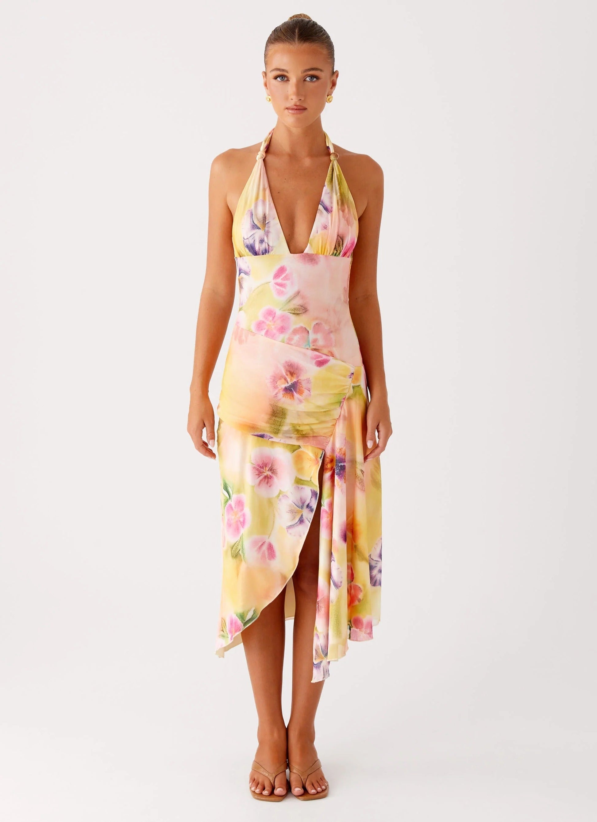 Front view of a woman wearing the yellow, pink, and purple floral midi dress with a V-neck halter for women.