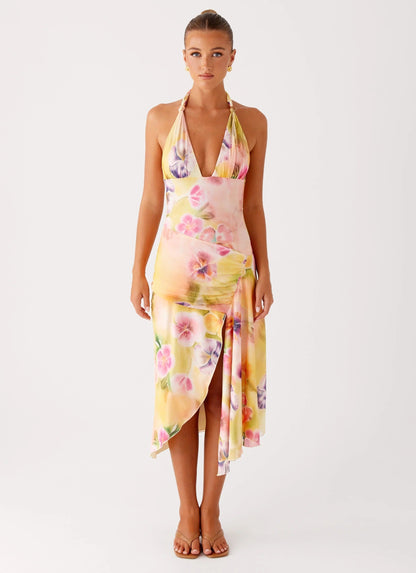 Front view of a woman wearing the yellow, pink, and purple floral midi dress with a V-neck halter for women.