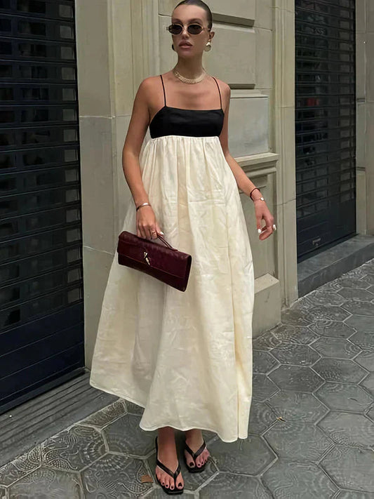 Cream and black color-block maxi dress with spaghetti straps for women, styled with sunglasses and a clutch.