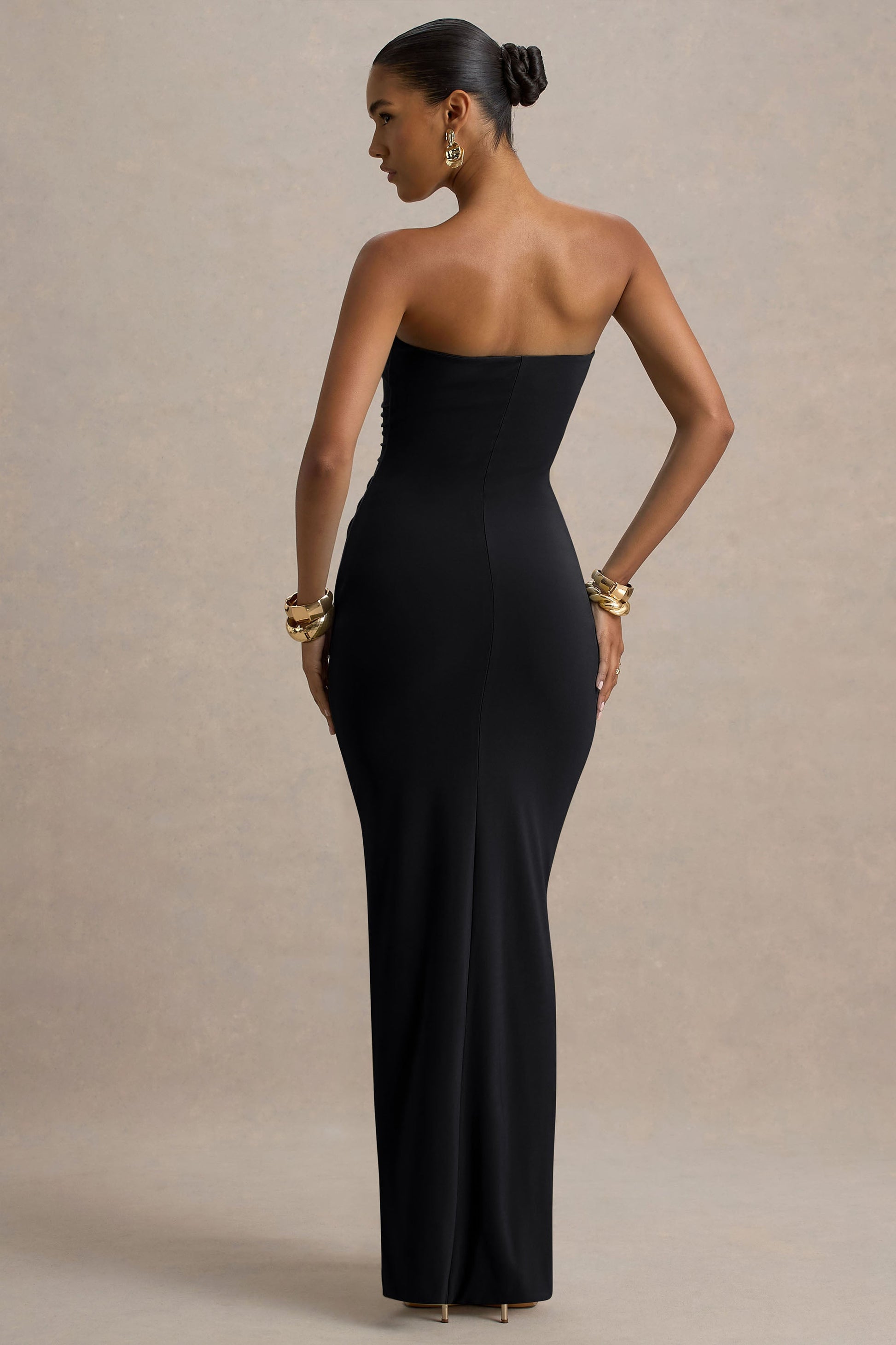 Back view of a sleek black strapless maxi dress, showing the form-fitting silhouette and clean lines.