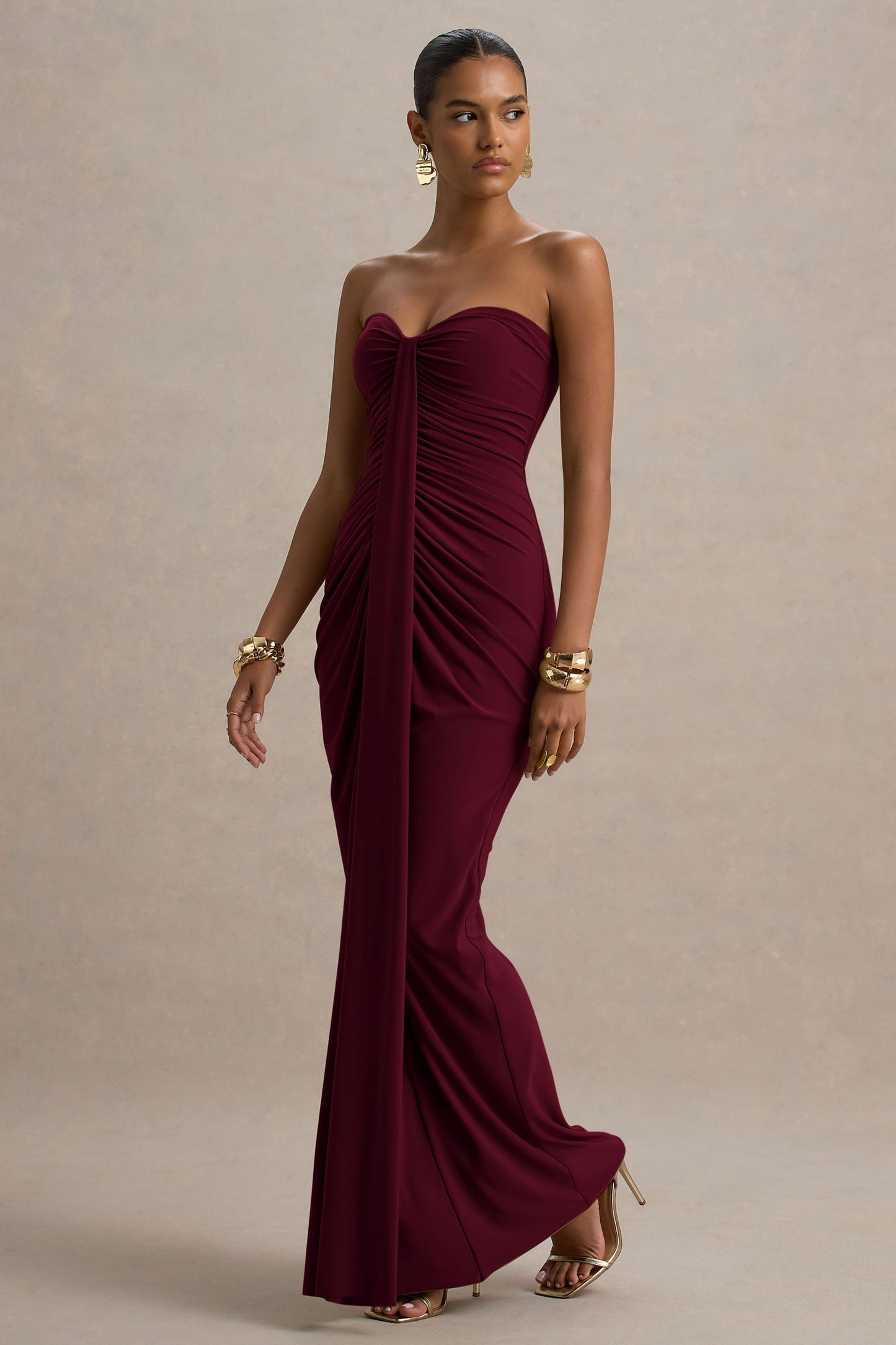 Side view of a burgundy strapless ruched maxi dress, showcasing the flow of the fabric and the floor-length design.