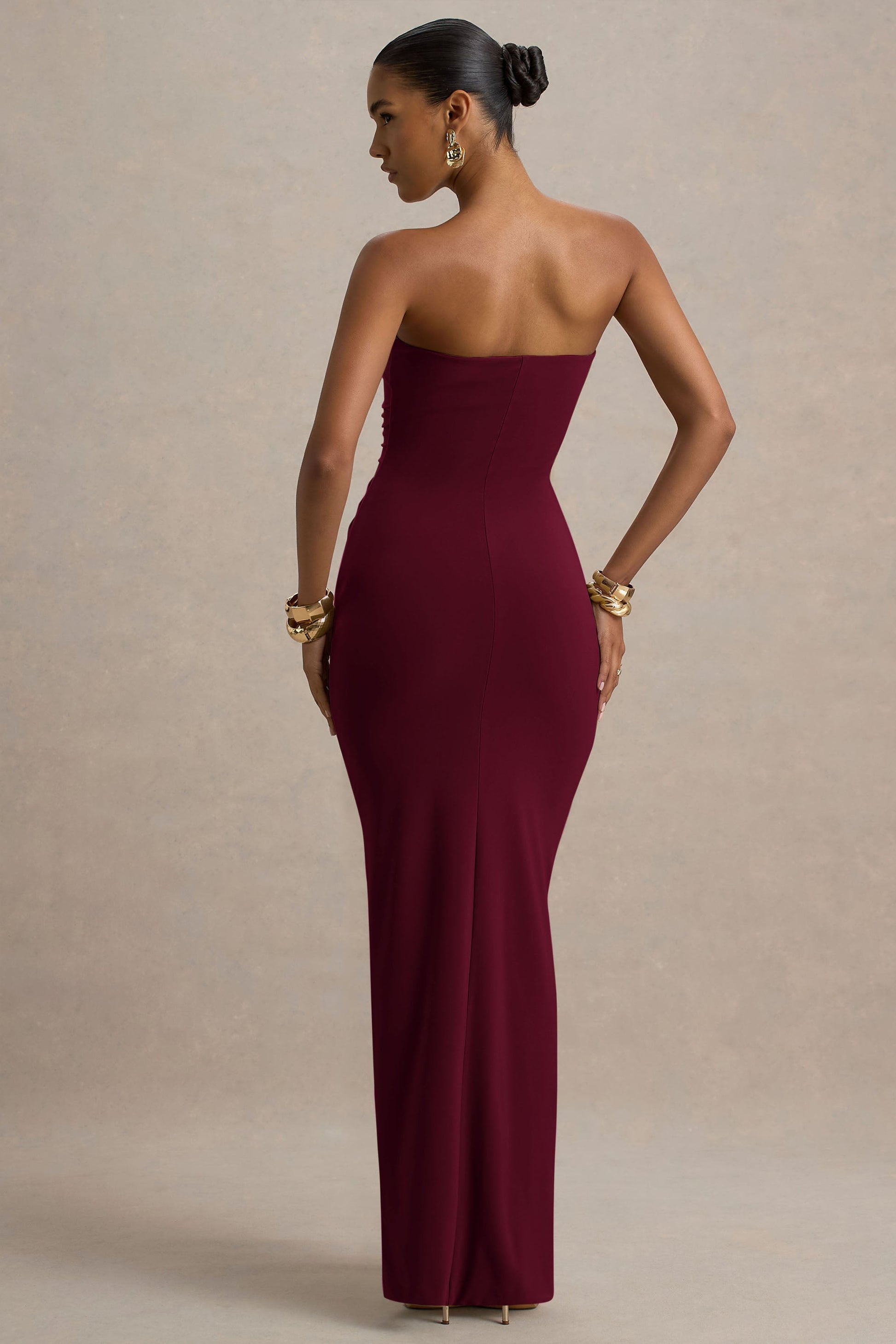 Back view of a burgundy strapless ruched maxi dress, emphasizing the form-fitting design and smooth back.