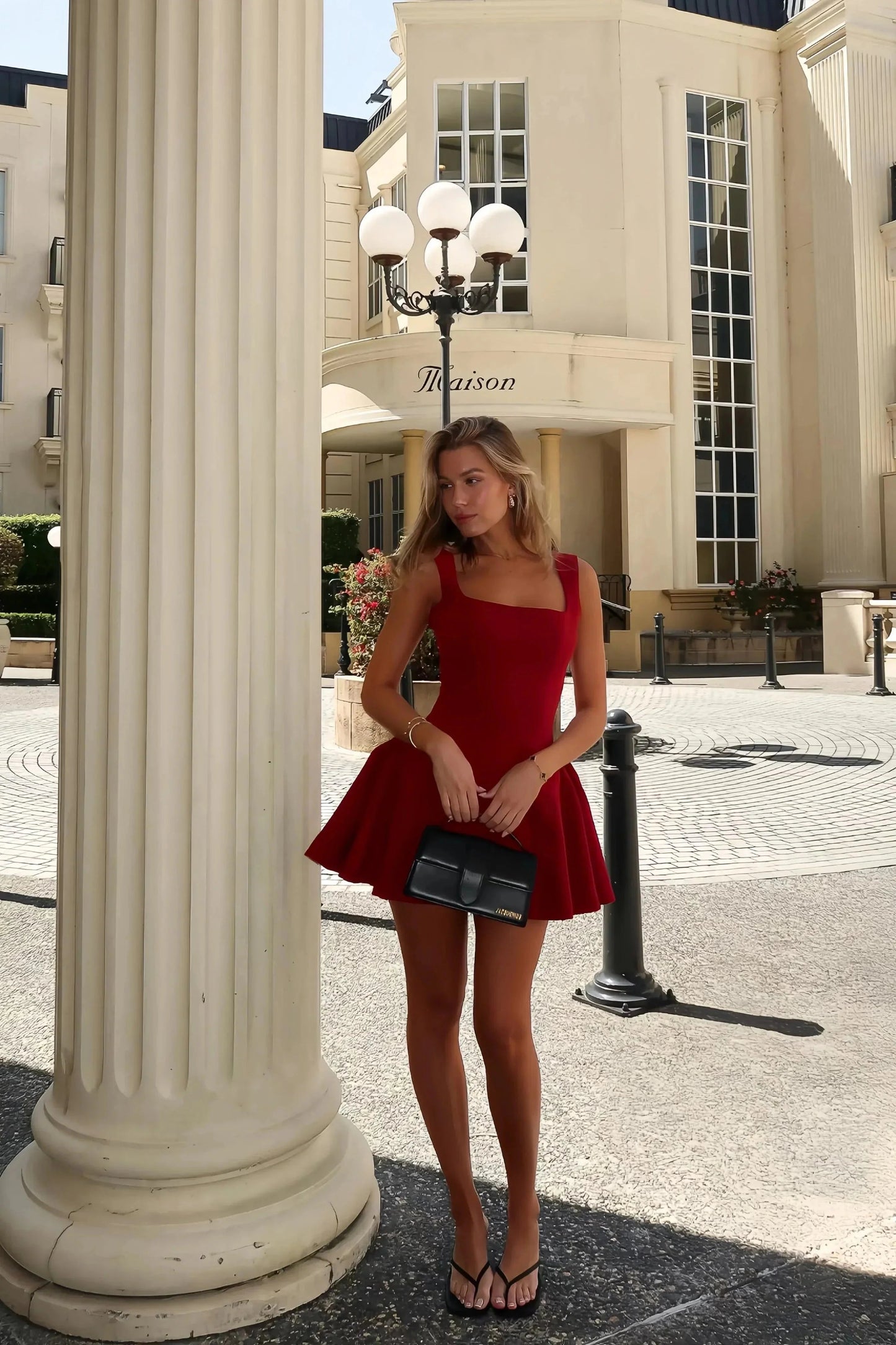 Red Lucy skater mini dress with a fitted top and a voluminous skirt, worn with black flip-flops and a small black top-handle bag.