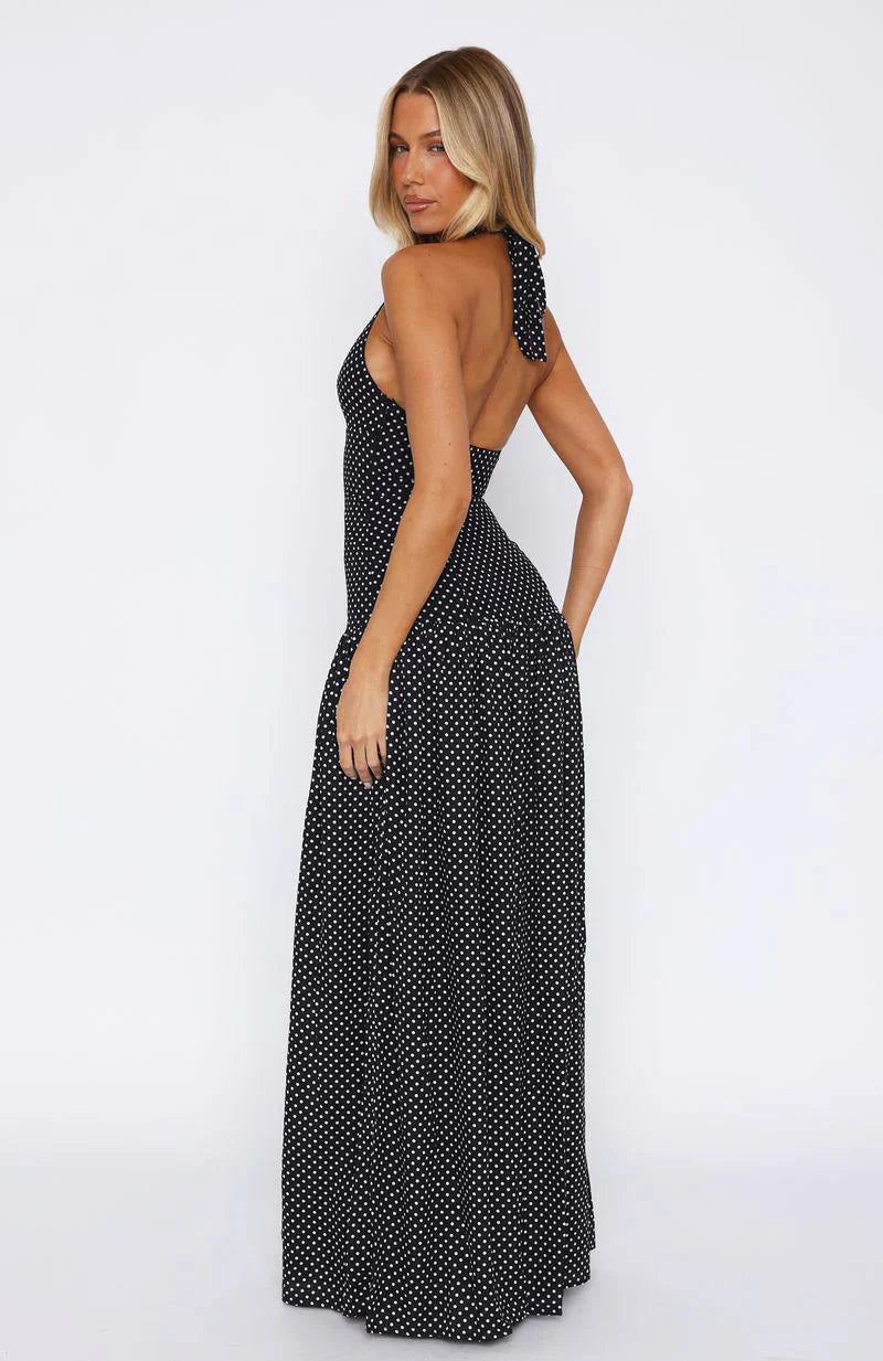 Back view of the black polka dot maxi dress, highlighting the halter tie and elegant drape.