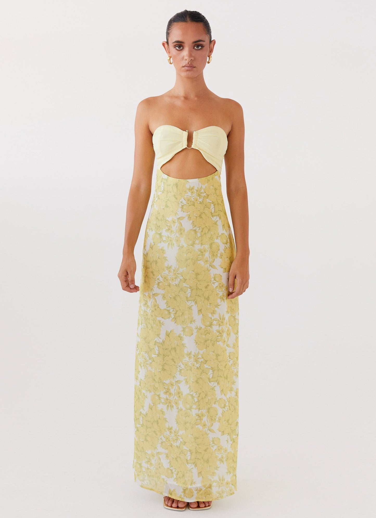 Front view of Lyra Floral Maxi Dress in yellow with white floral print, strapless design, and waist cutout.