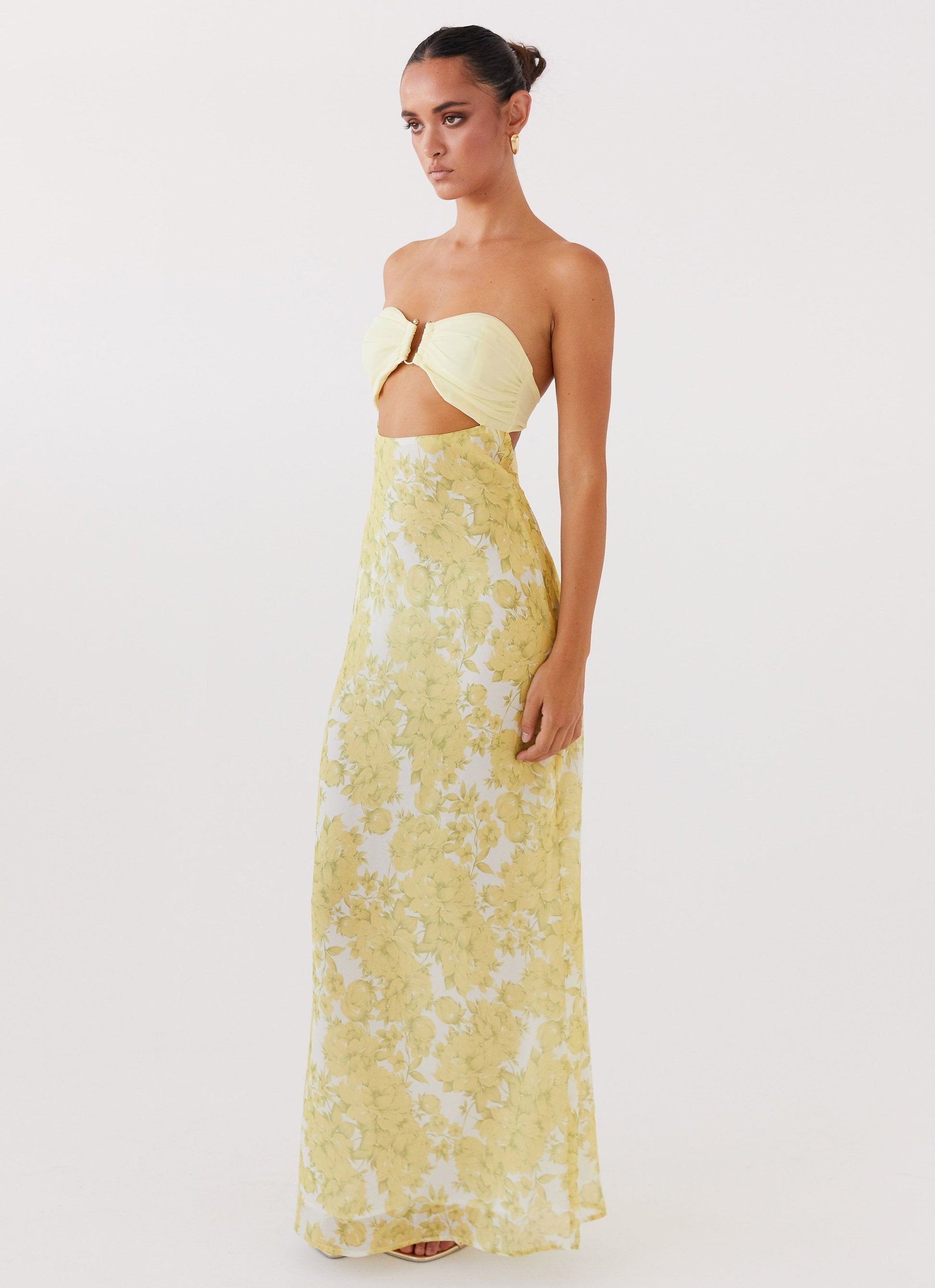 Side view of Lyra Floral Maxi Dress in yellow with white floral print, strapless top, and midriff cutout.