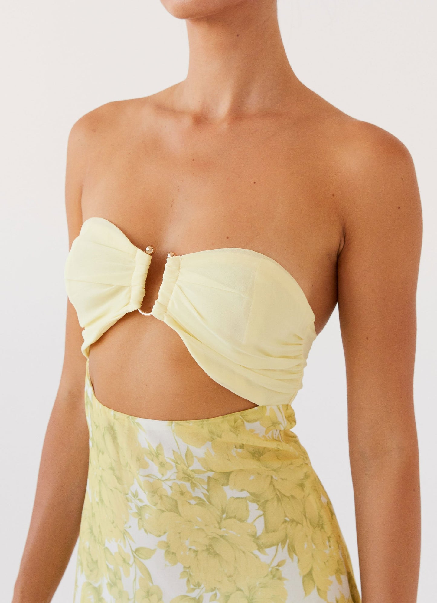 Close-up of the yellow Lyra Floral Maxi Dress bodice, showing ruched strapless top and waist cutout.