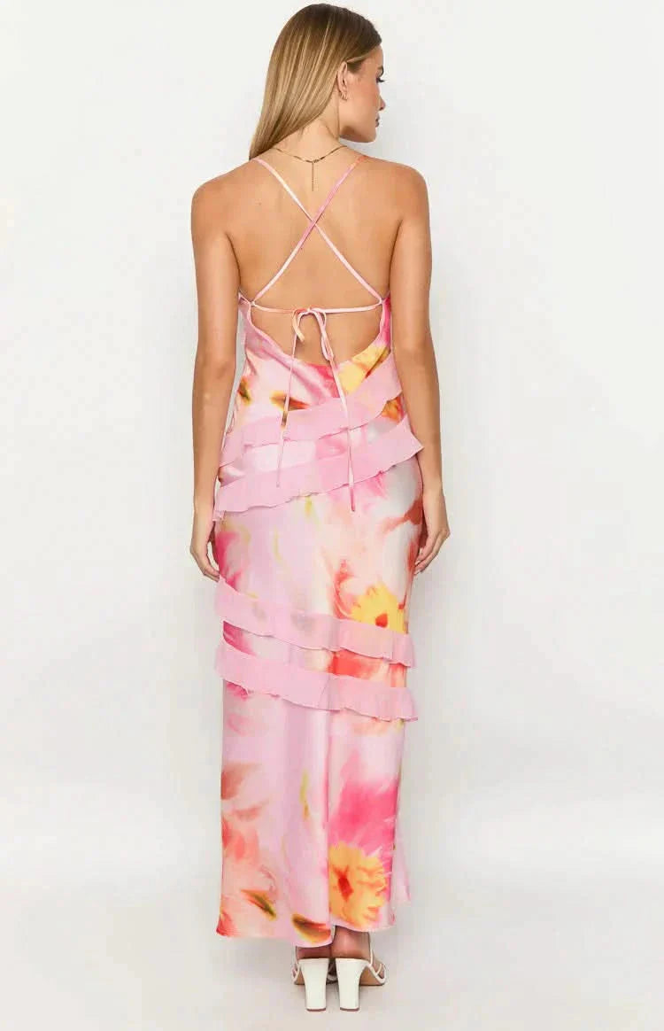 Back view of a pink floral Madeline ruffle maxi dress, showcasing the criss-cross back straps and tiered ruffles over the colorful pattern.