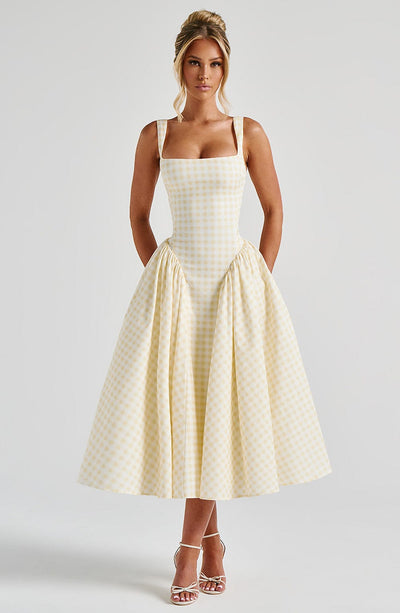 Light yellow gingham midi dress with structured bodice and voluminous skirt, paired with white heels.