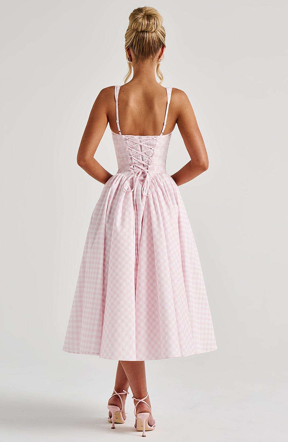 Back view of a pink gingham midi dress, showcasing the lace-up corset detail on the bodice.