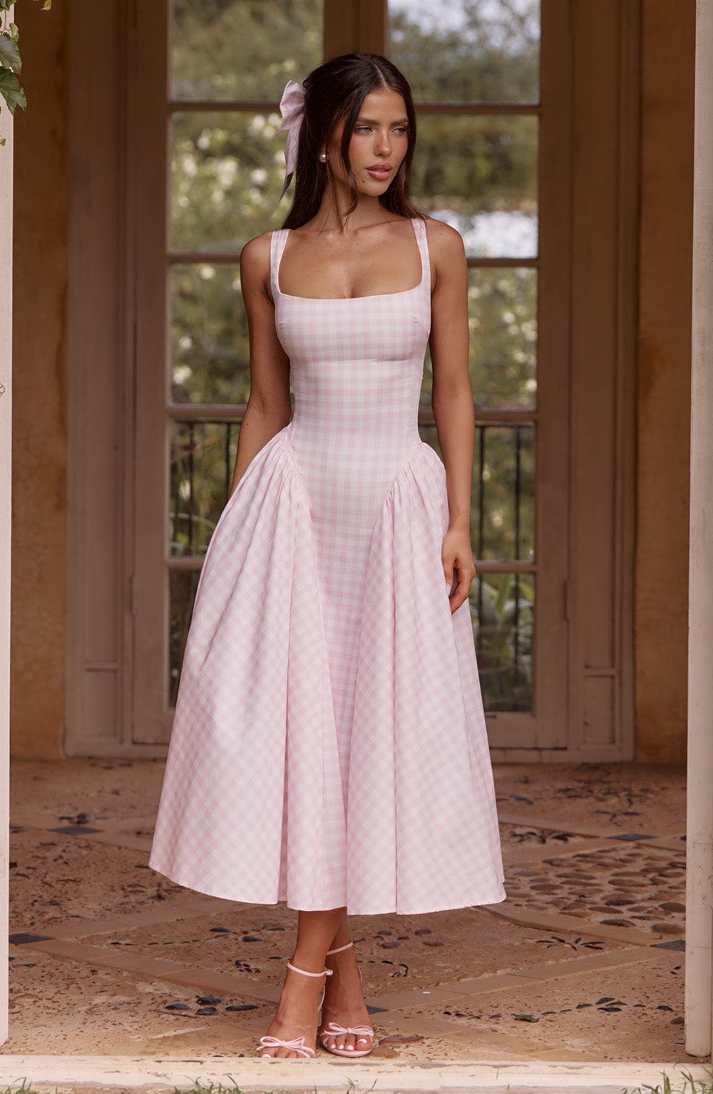 Pink gingham midi dress with square neckline and full pleated skirt, styled with pink bow heels.