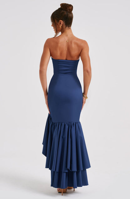 Back view of a woman in a strapless navy blue Marlowe Ruffle Maxi Dress, showcasing the tiered mermaid skirt.