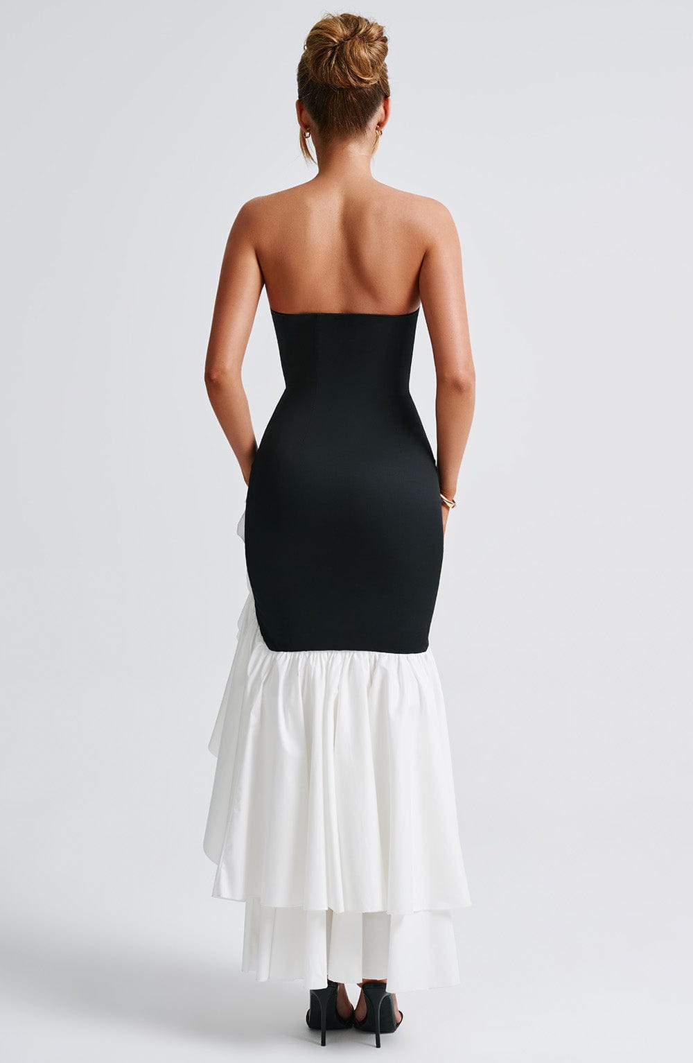 Back view of the Marlowe Ruffle Maxi Dress in black with a white high-low ruffle skirt, showing the strapless back and layered skirt detail.