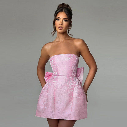 Pink strapless mini dress with delicate floral jacquard texture and a prominent bow accent on the side, a playful suit dress option.
