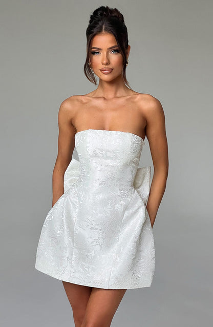 White strapless mini dress with subtle floral jacquard pattern and large side bow detail, perfect for a wedding dress.