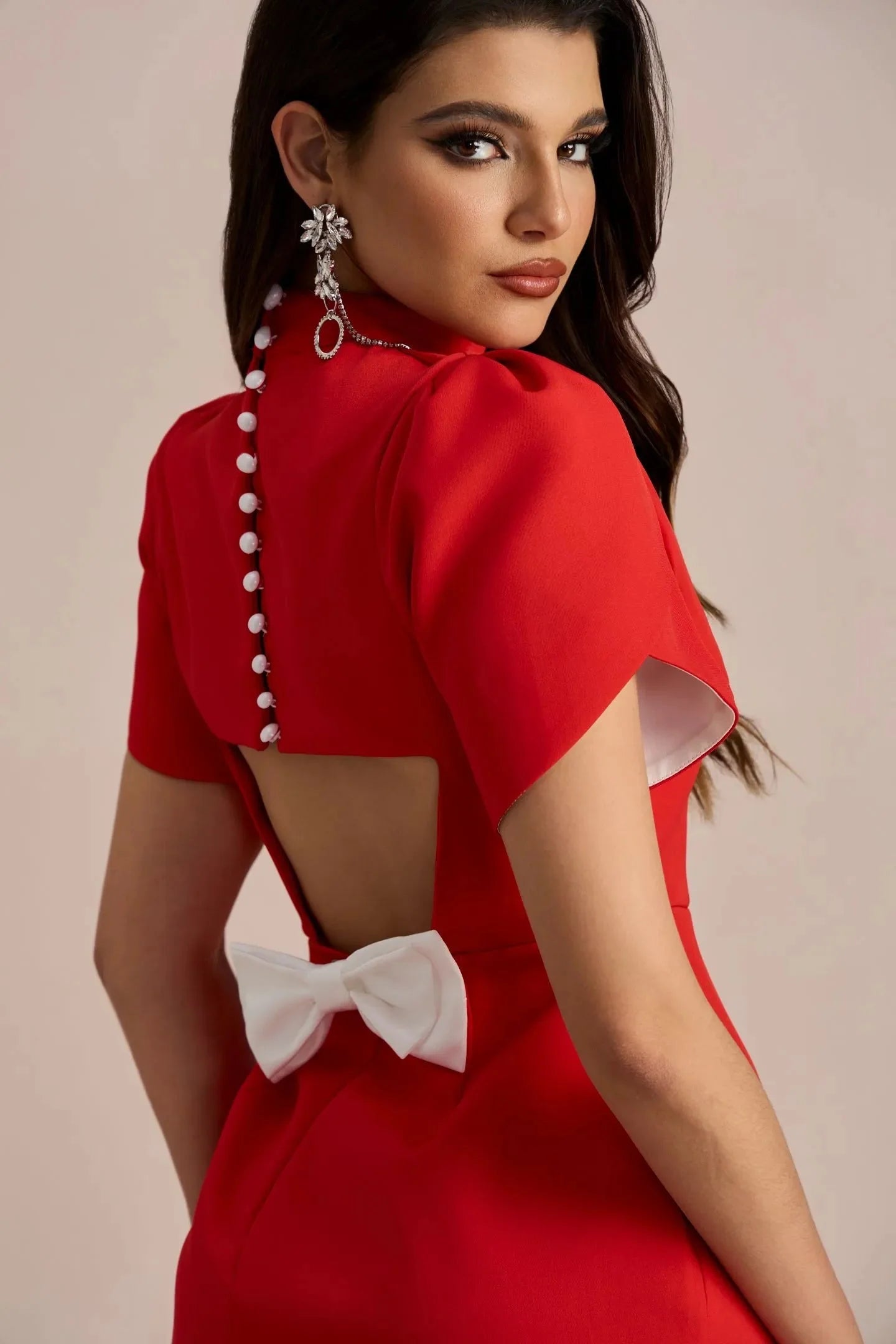 Close-up back view of the red Nora Bow Mini Dress, showing the pearl buttons, open back, and white bow detail.