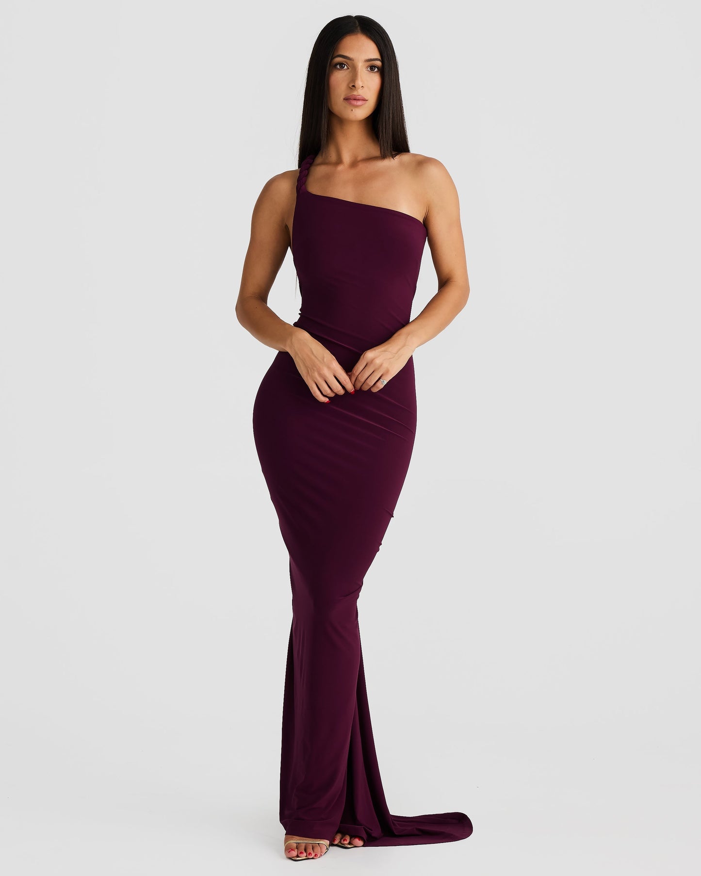 Front view of a woman posing in a plum purple Paulina backless maxi dress with a unique one-shoulder design.