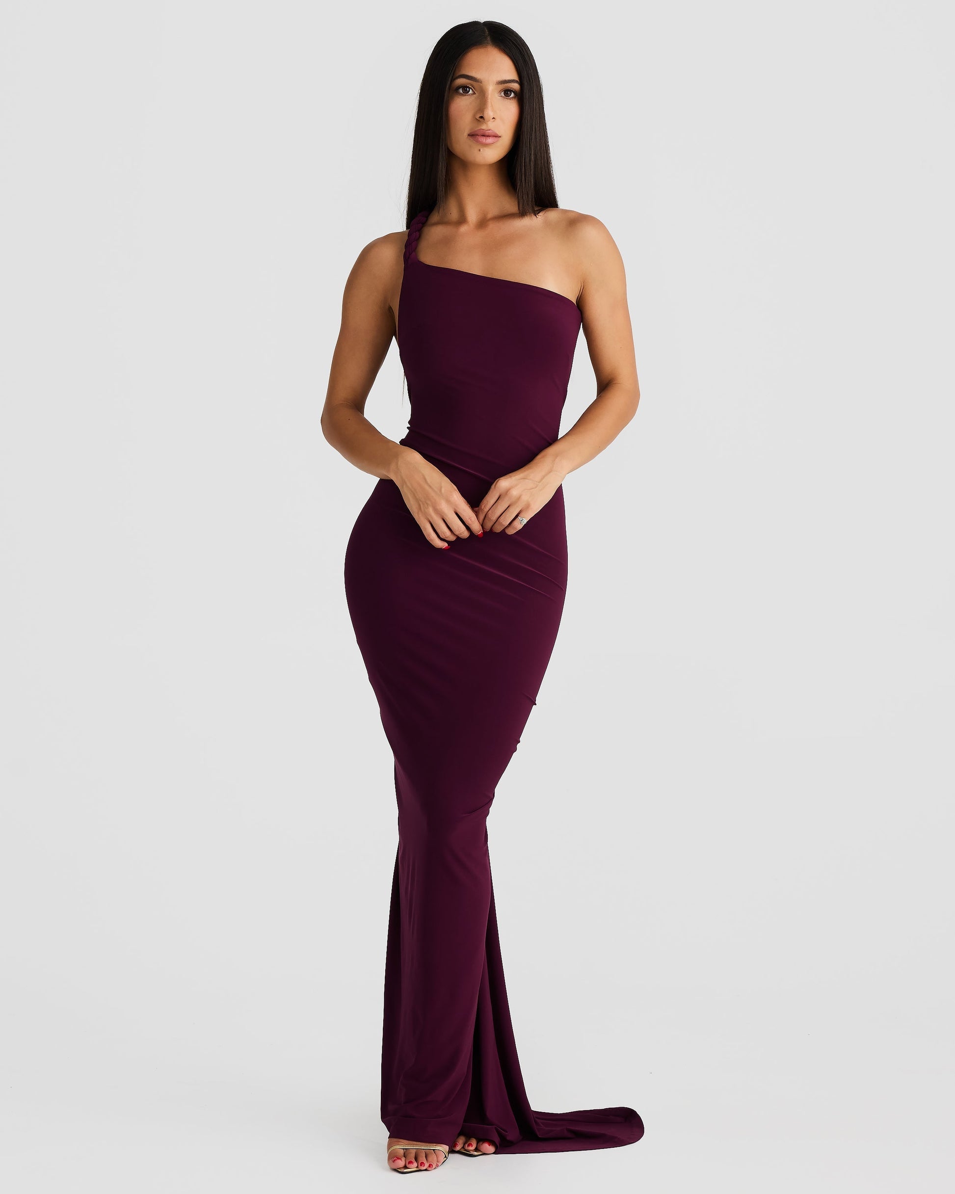 Front view of a woman posing in a plum purple Paulina backless maxi dress with a unique one-shoulder design.