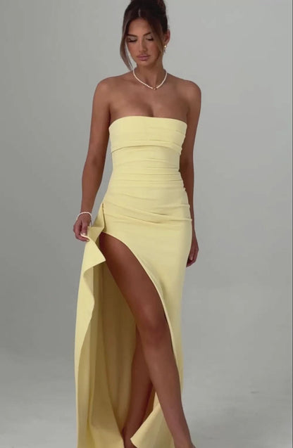 Light yellow strapless ruched maxi dress with a high side slit, showcasing the flowing fabric and elegant design.