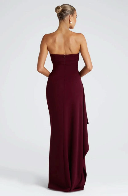 Back view of a burgundy strapless ruched maxi dress, showing the elegant silhouette and draped skirt.