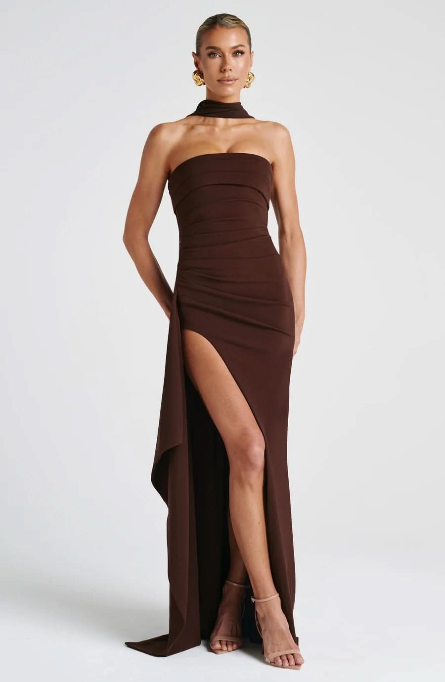 Front view of a strapless brown ruched maxi dress with a high slit and halter neck detail, perfect for elegant occasions.