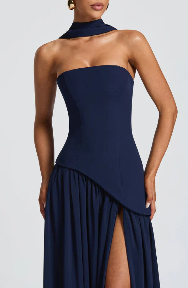 Close-up of the navy blue Rhea Asymmetrical Maxi Dress bodice, highlighting the strapless design and draped asymmetrical waist.