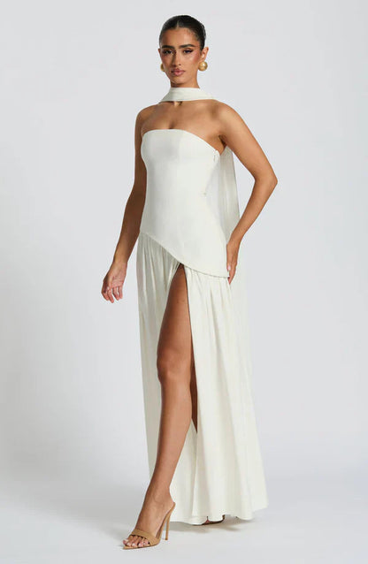 Full length view of an ivory Rhea Asymmetrical Maxi Dress, with a strapless bodice, high slit, and elegant choker detail.