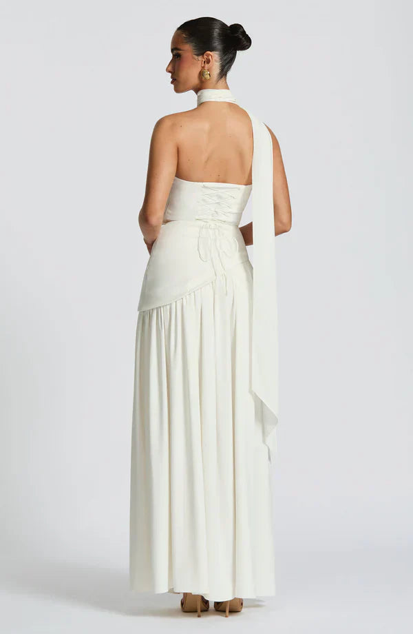 Back of the ivory Rhea Asymmetrical Maxi Dress, displaying the lace-up back and the long, flowing scarf accent.