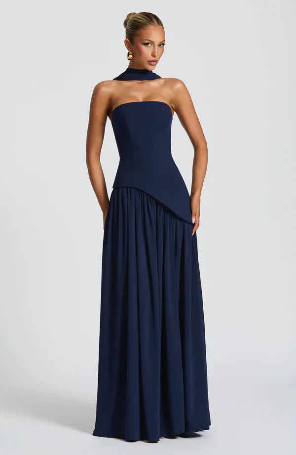 Navy blue strapless maxi dress with an asymmetrical peplum bodice and relaxed skirt, complete with a matching choker.