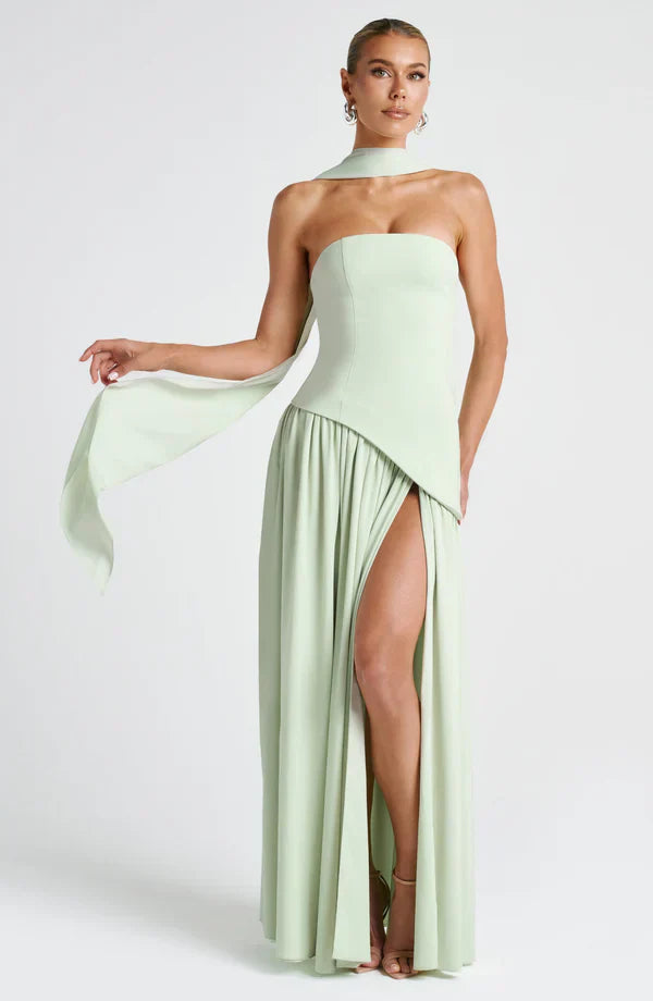 Full-length light green asymmetrical maxi dress with a strapless bodice, high leg slit, and flowing neck scarf detail.