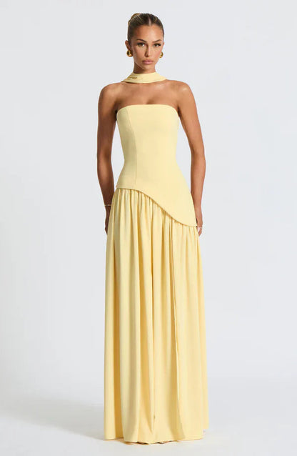 Pale yellow strapless maxi dress with a unique asymmetrical peplum design and a delicate matching choker.