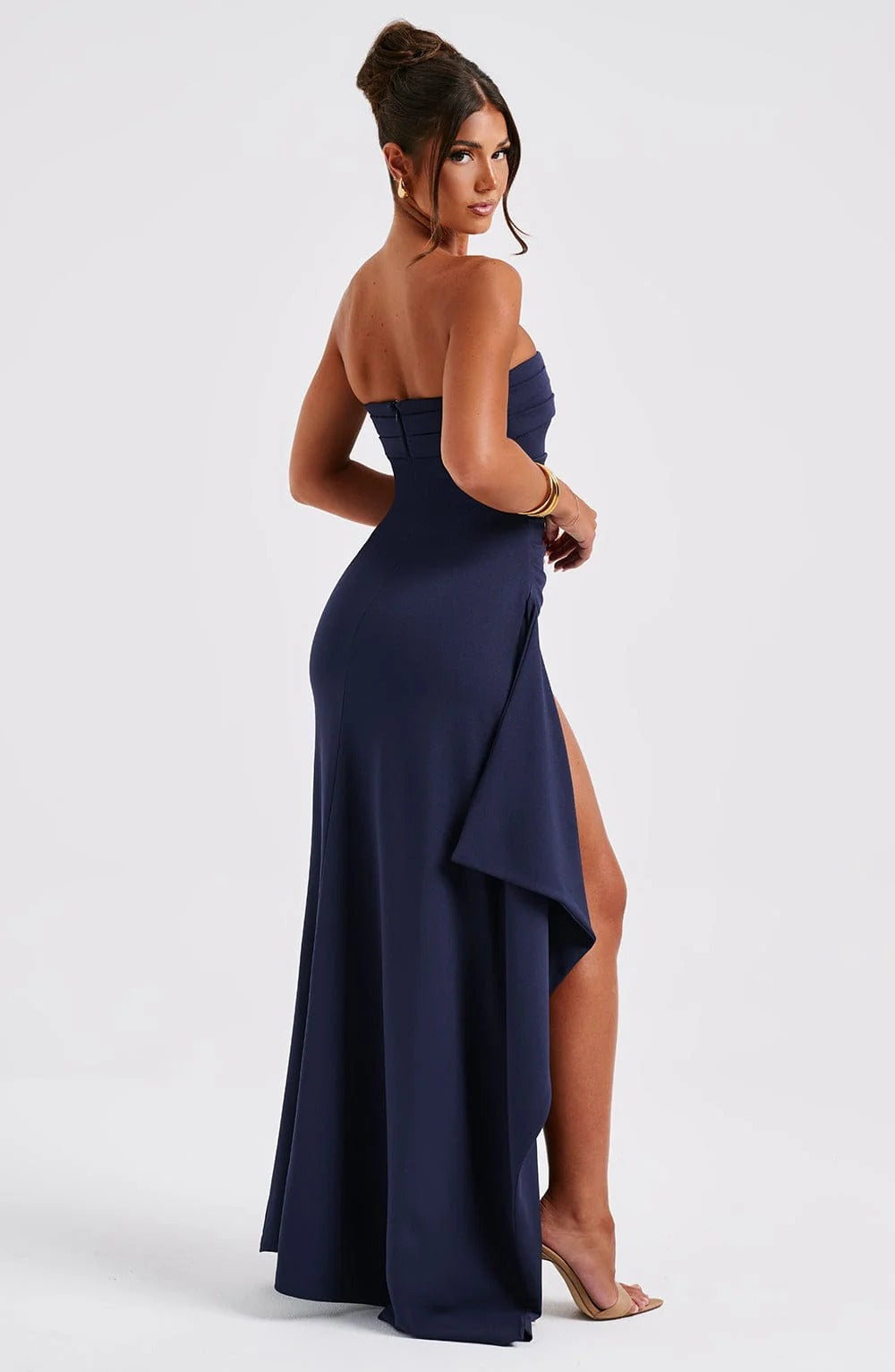 Back angled view of the navy blue Rosie Ruched Maxi Dress, showing the strapless design and leg slit.