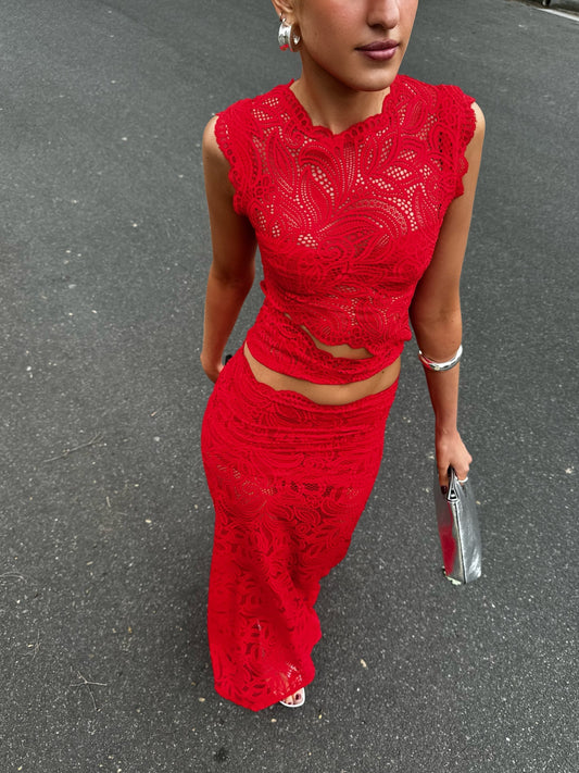 Top-down view of a woman wearing a vibrant red lace maxi dress set with cutouts, holding a silver clutch.